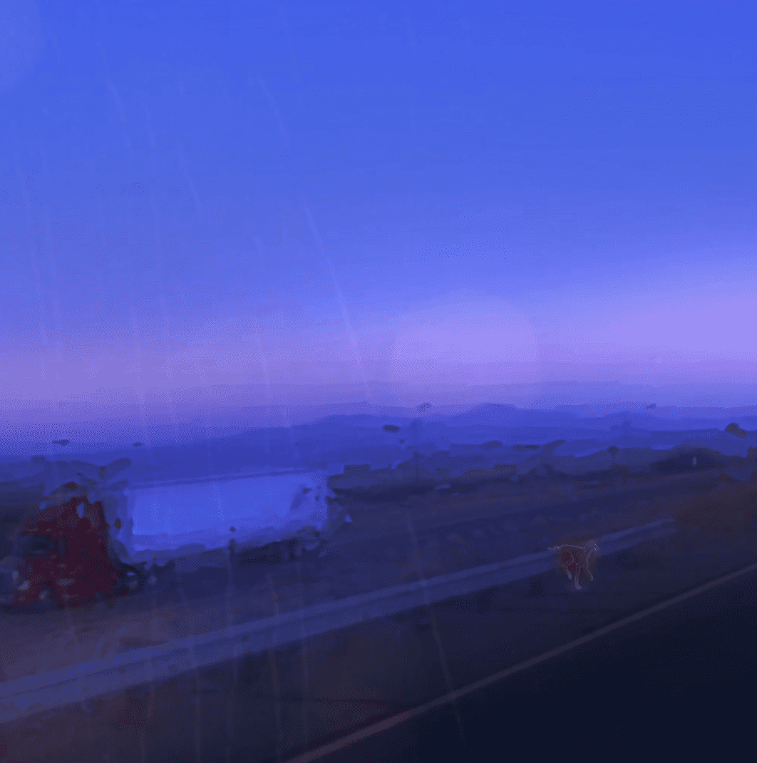 A highly blurry image of a highway at dusk. The scene is mostly blue, with a strip of pink near the horizon..
