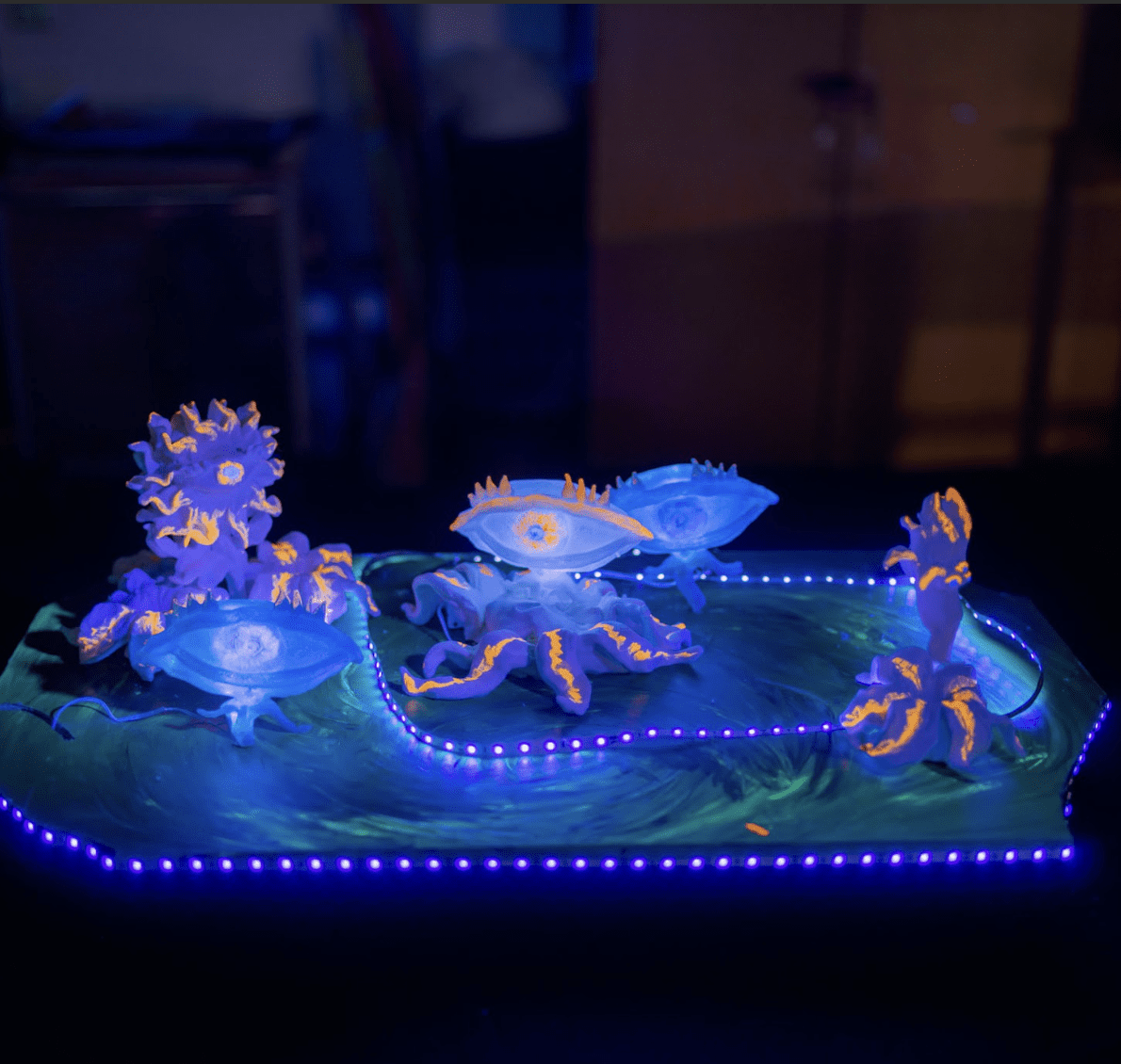 A small, glowing sculpture of anthropomorphic aliens. The sculpture glows in blue light.