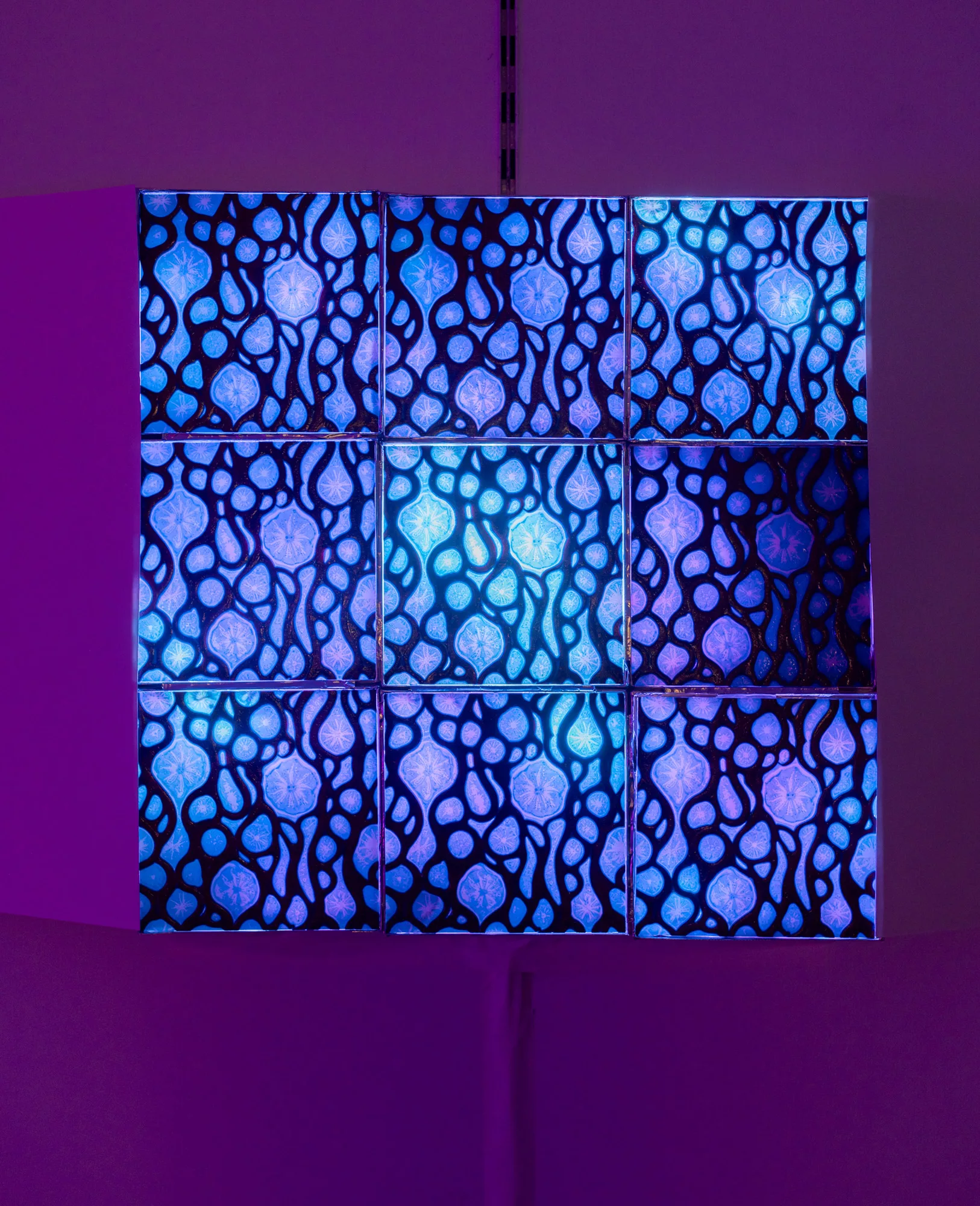 A square of tiles, three rows of three, glow purple and blue. Each tile is patterned with an organic, curving web that obstructs the light.