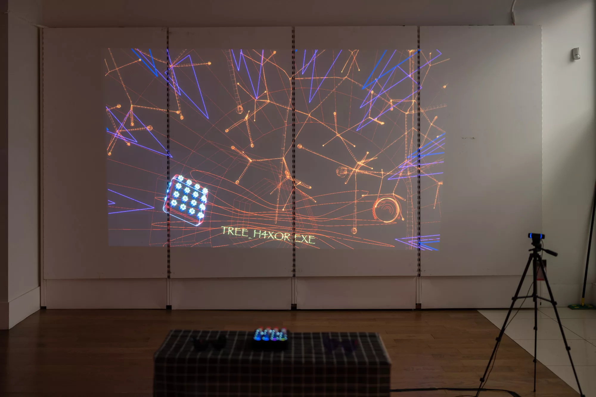 A video projected onto a wall with abstract orange and blue lines. Text in the video reads 