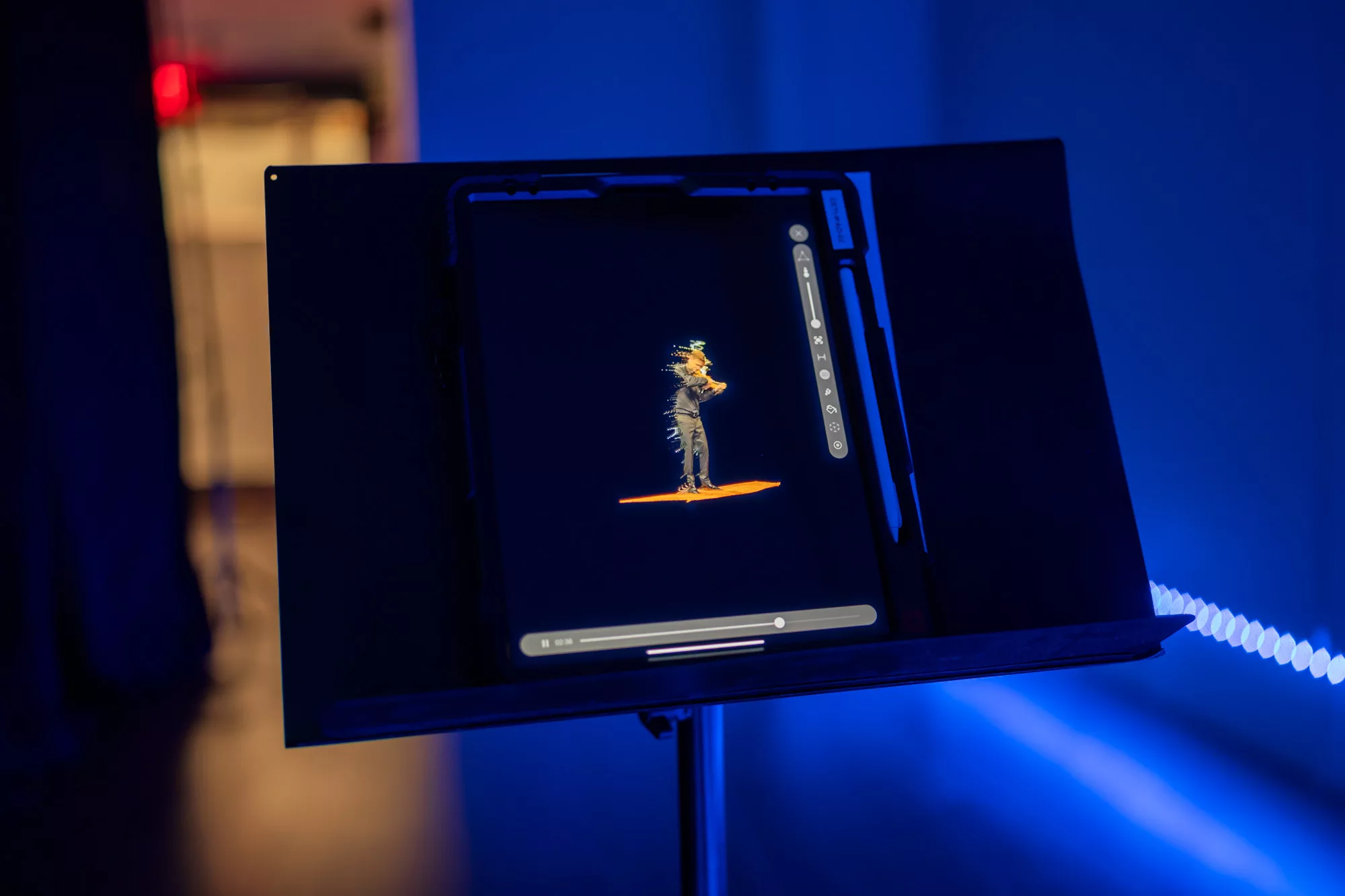 An ipad sits on a music stand. a video of a violinist plays on the ipad. The figure is slightly distorted so that gold light trails behind them.